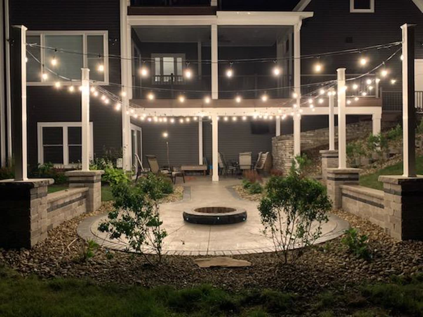 Backyard patio with seat walls and string lights at night