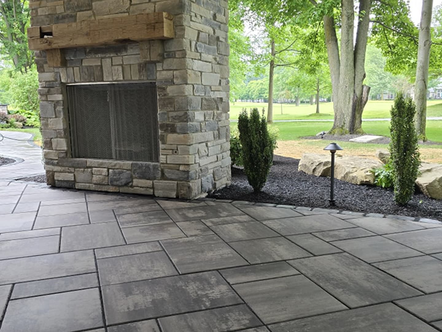 Covered stone fireplace overlooking a finished paver patio