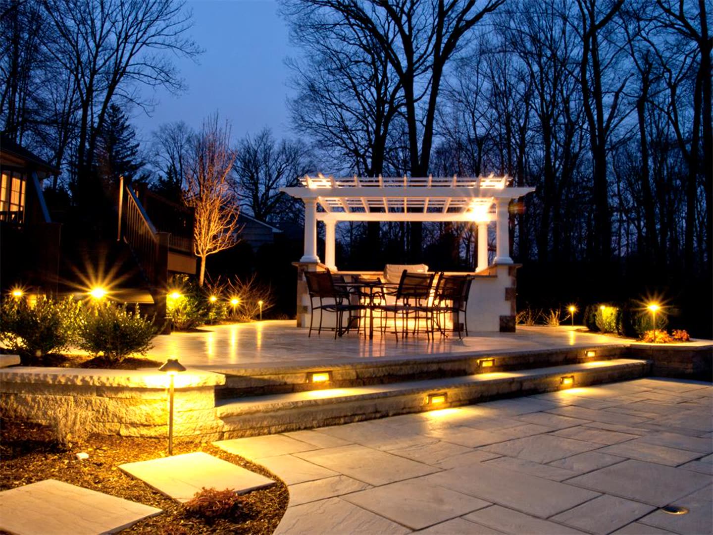 Pergola and paver patio illuminated with integrated landscape lighting