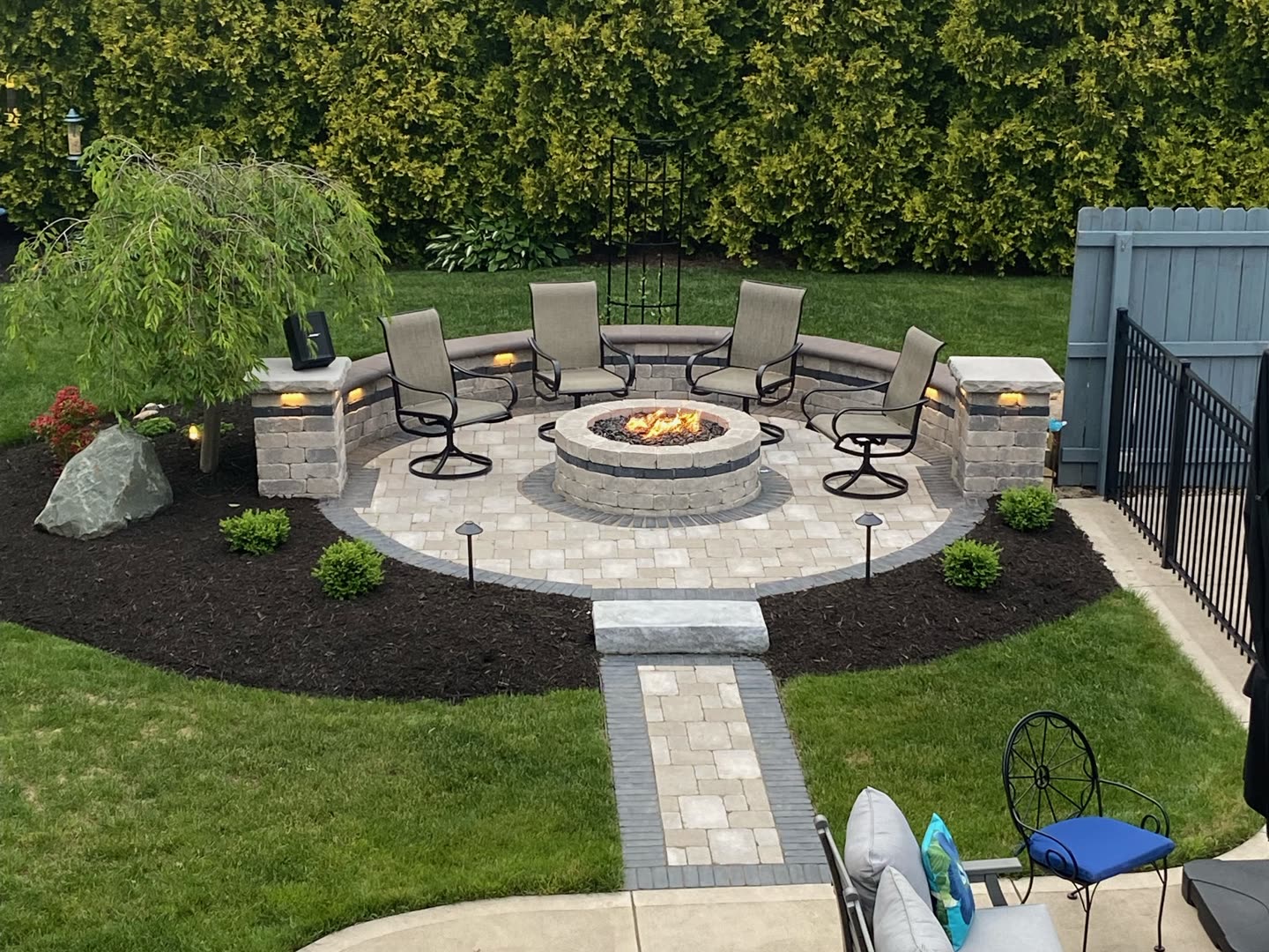 Circular fire pit patio connected to the house by a paver walkway