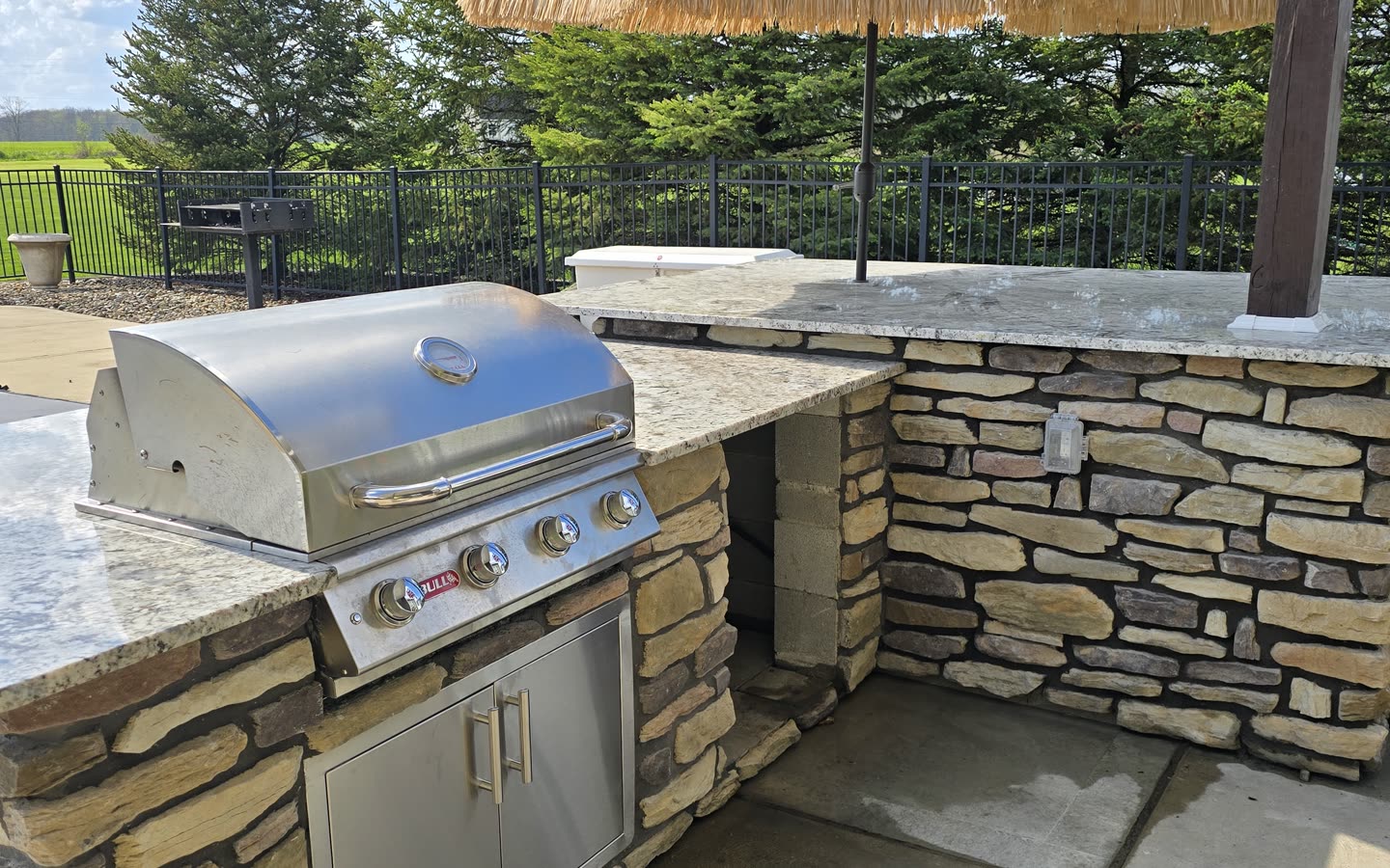 Built-in outdoor kitchen with stainless steel grill and stone counters